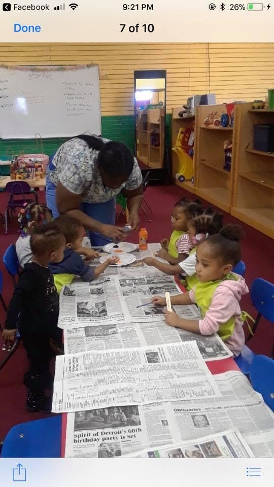 Adult and children painting at a table covered with newspapers