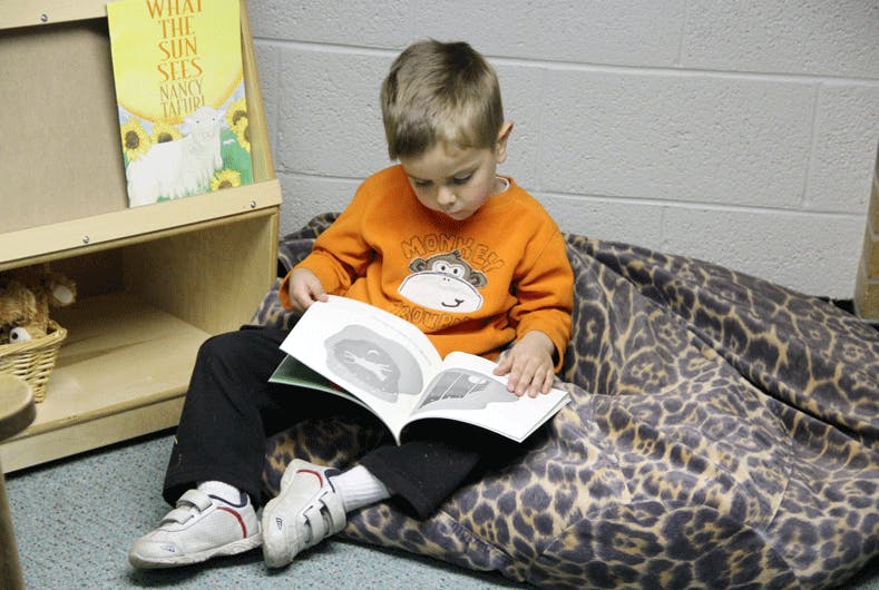 Child sitting on a beanbag and reading a book