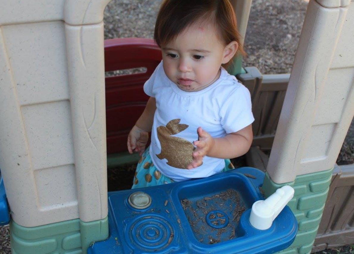 Child holding a toy in a play kitchen
