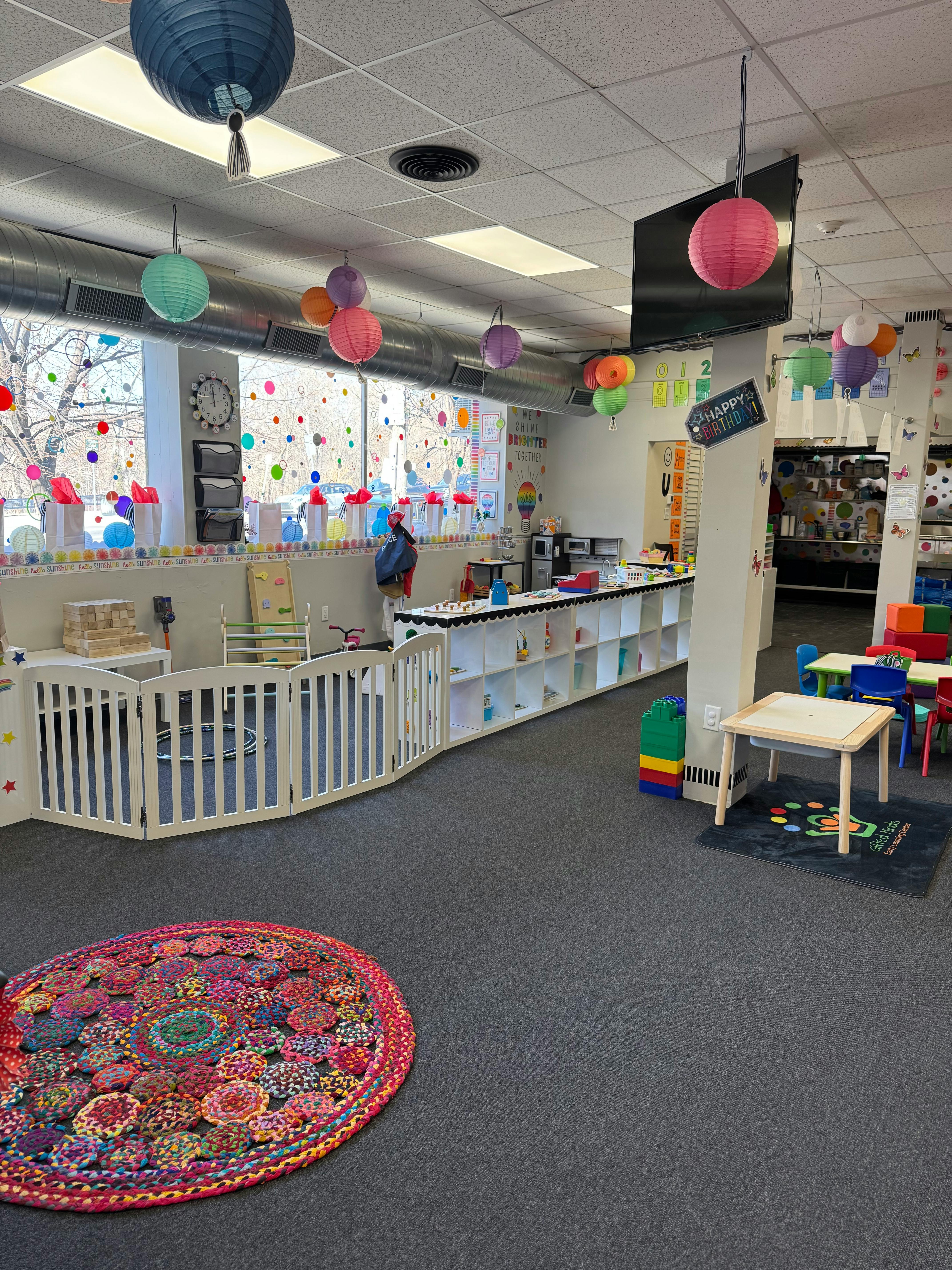 Daycare classroom with playpen, tables, and colorful decorations