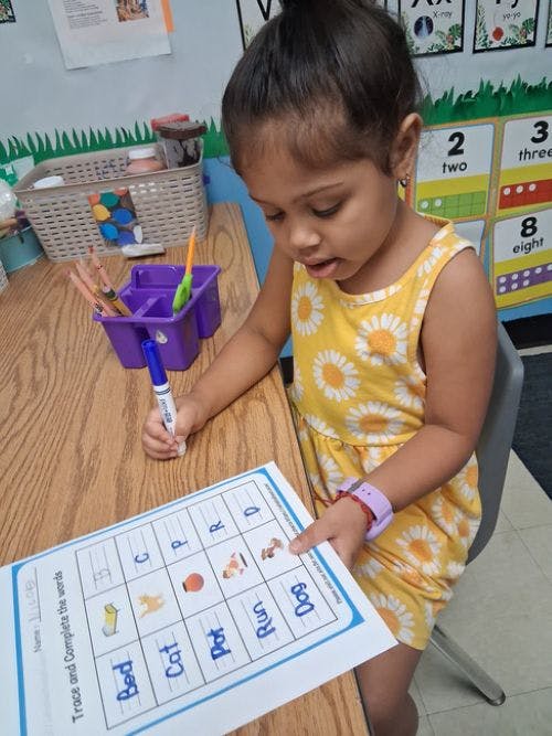 Child tracing words on a worksheet at a desk