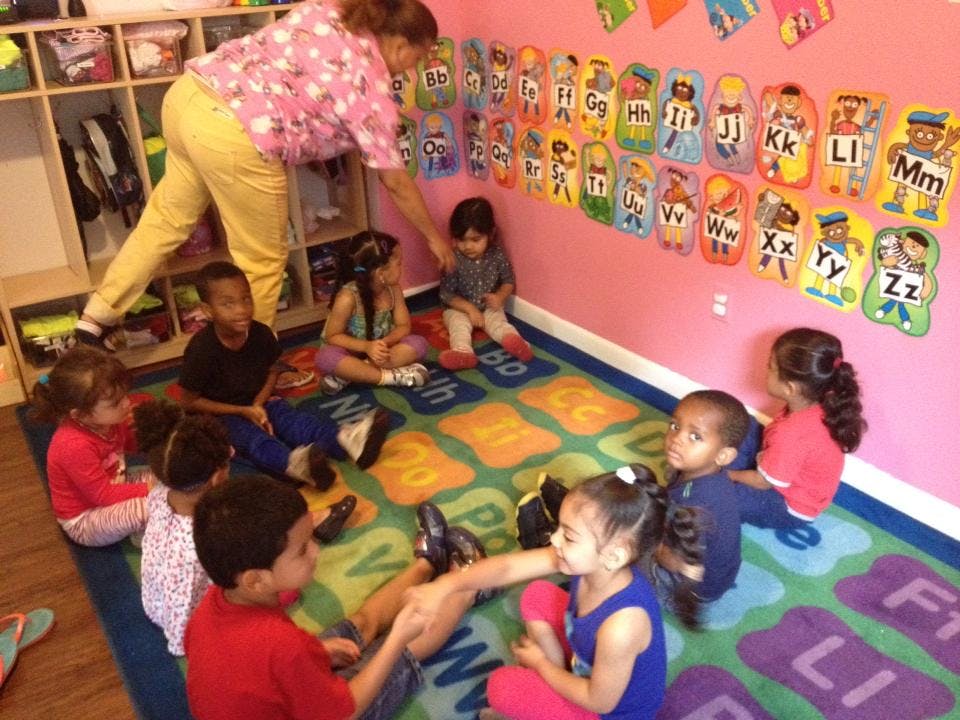 Adult interacting with children sitting on a rug in a classroom