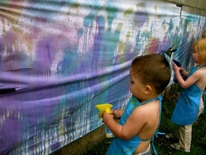 Two children spray painting a large canvas