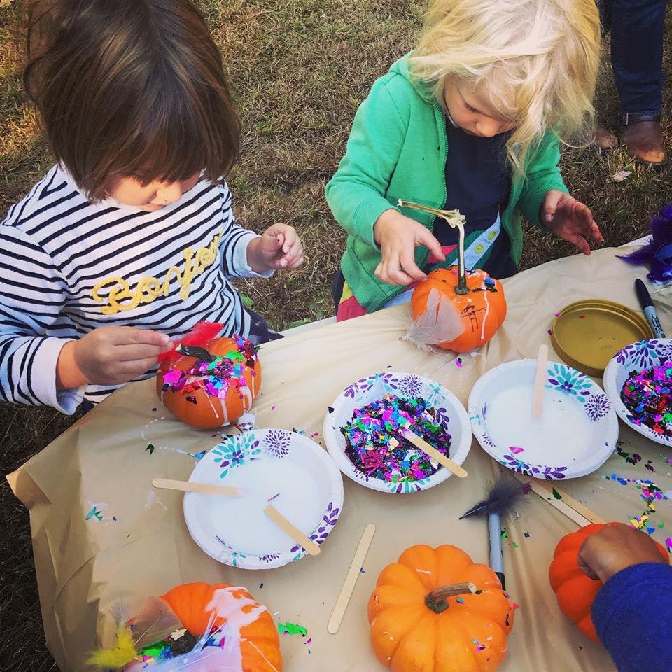 Two children decorating pumpkins with glitter and glue