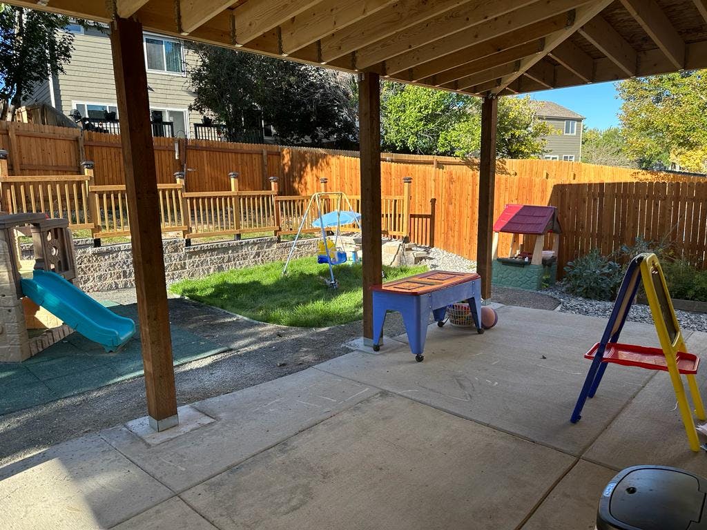 Patio under a wooden deck with a backyard playground
