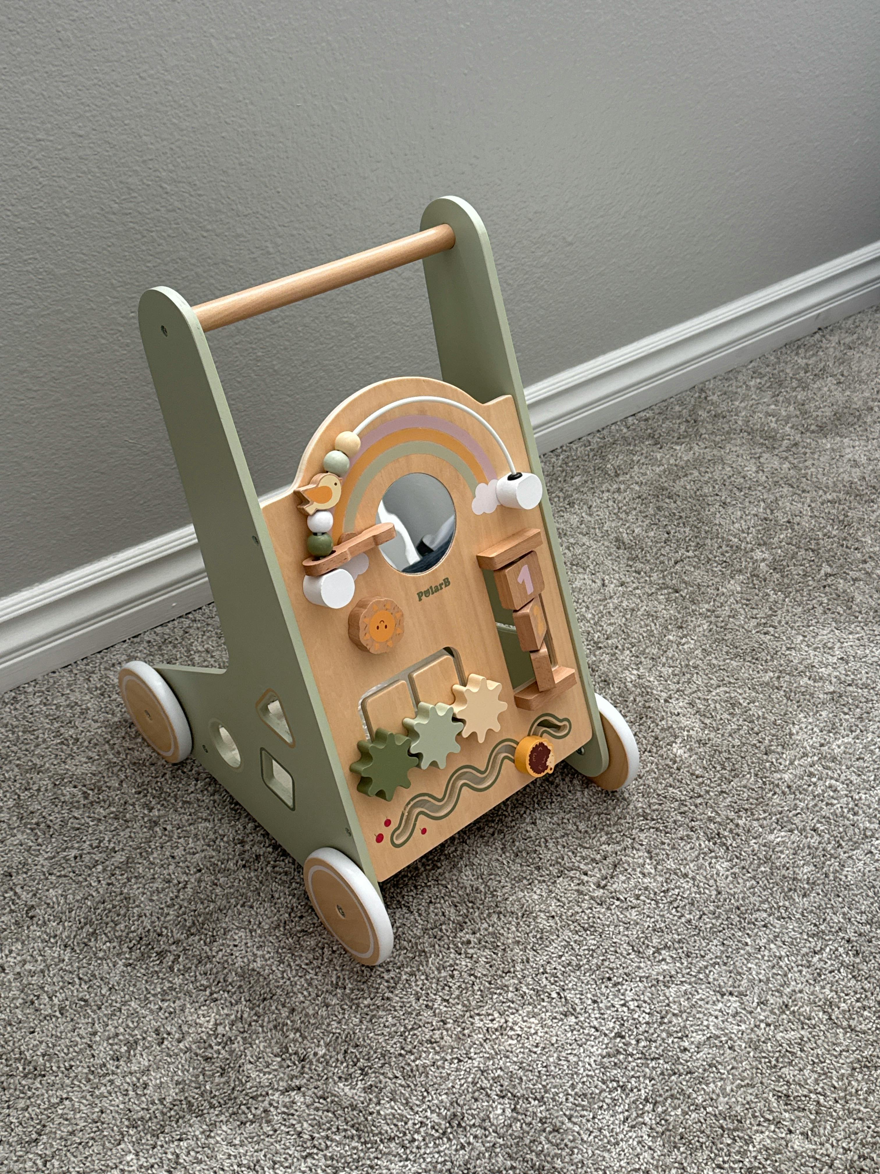 Wooden activity baby walker with gears and a mirror on a carpeted floor