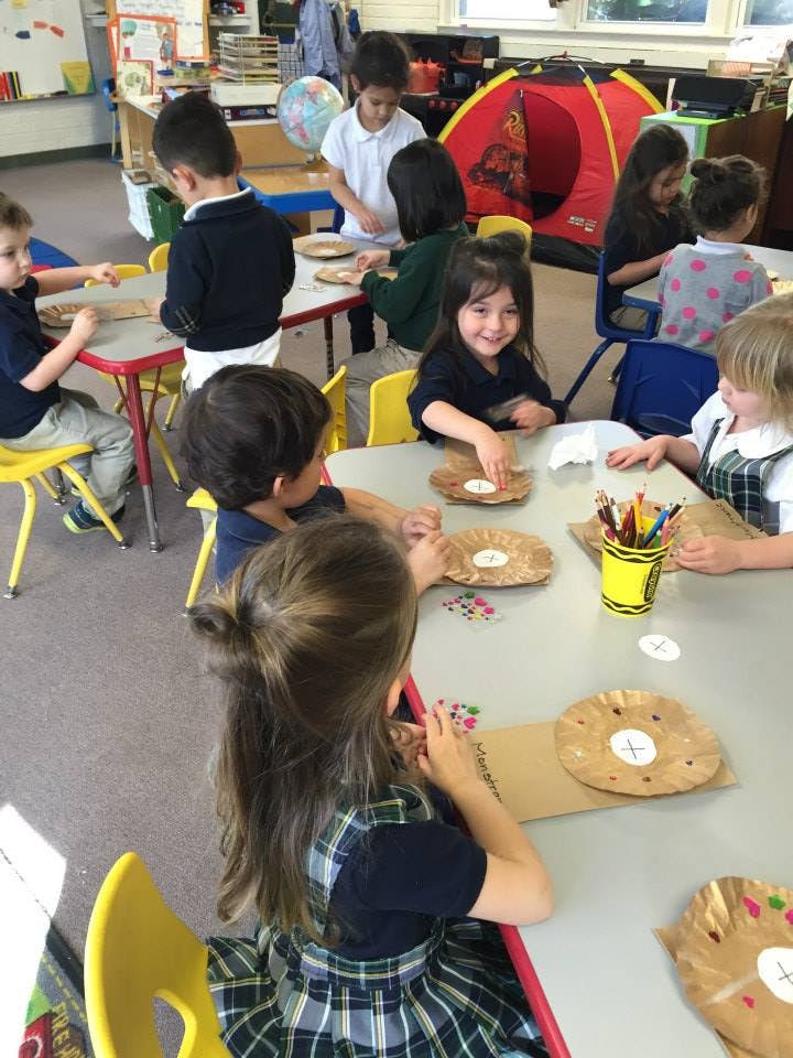 Children sitting at tables doing crafts in a classroom