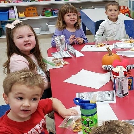 Children sitting at a red table in a classroom