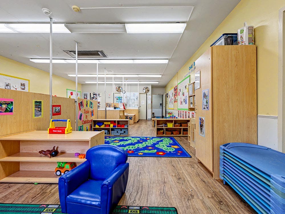 Empty classroom with cubbies, blue chair, and small cots