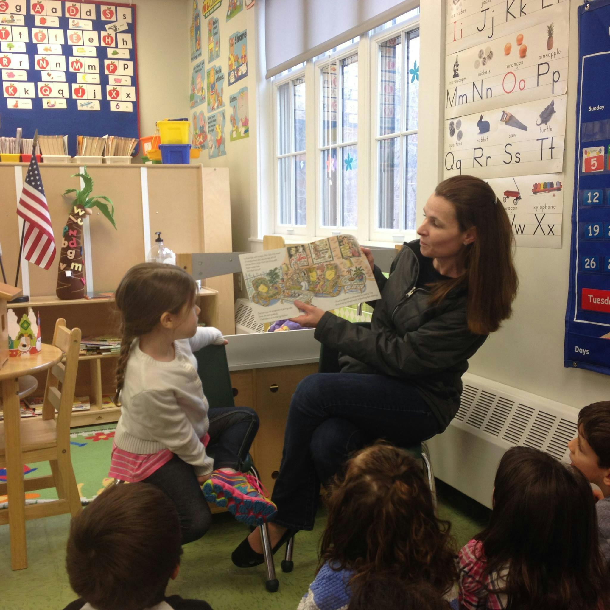 Person reading a book to children in a classroom