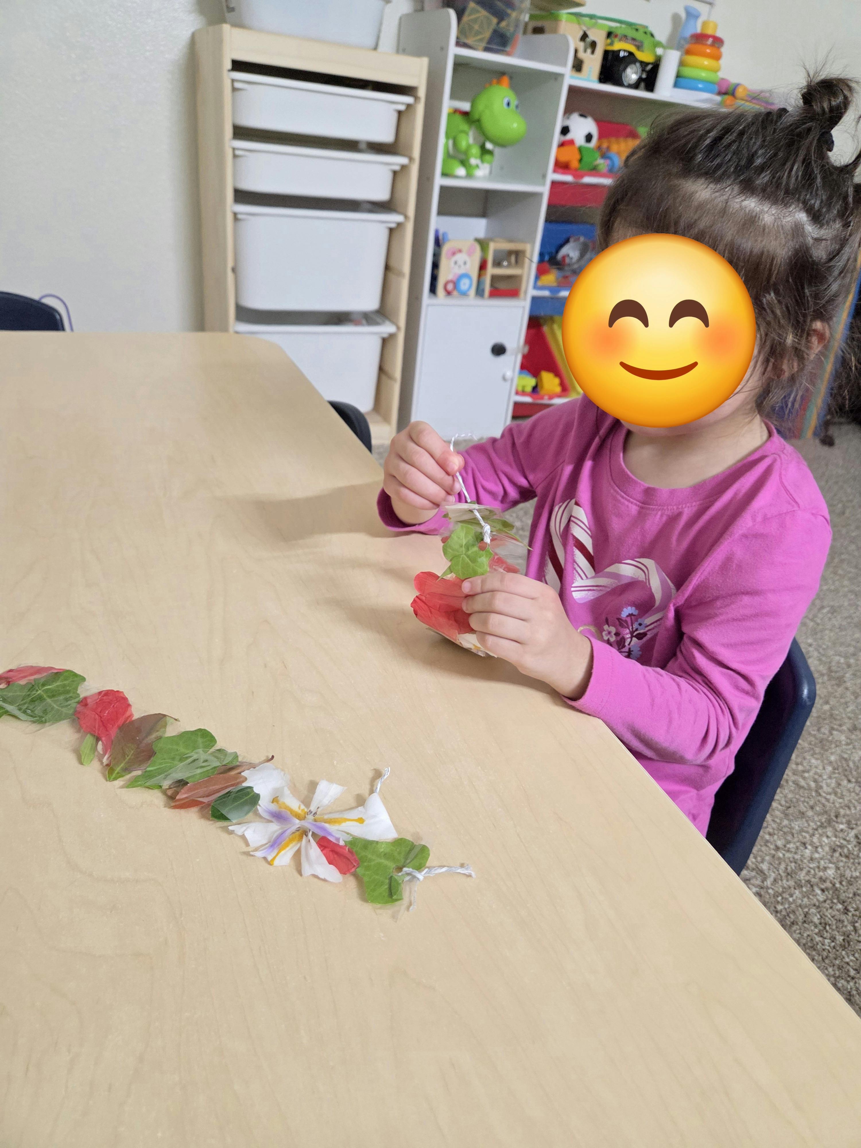Child crafting with leaves and flower petals at a table