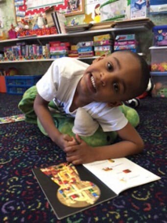 Child on floor with open book, looking up