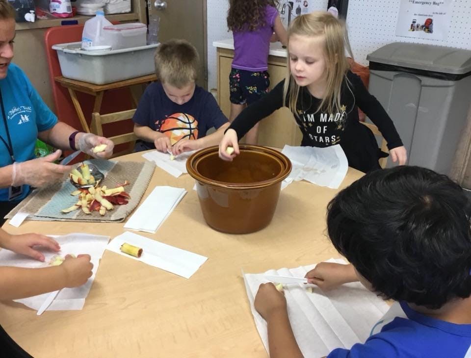 Adult and children preparing food at a table