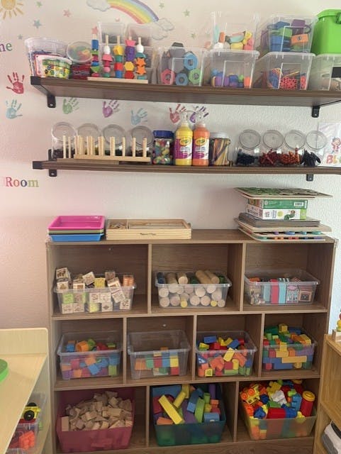 Wooden shelving unit stocked with bins of various building blocks and toys