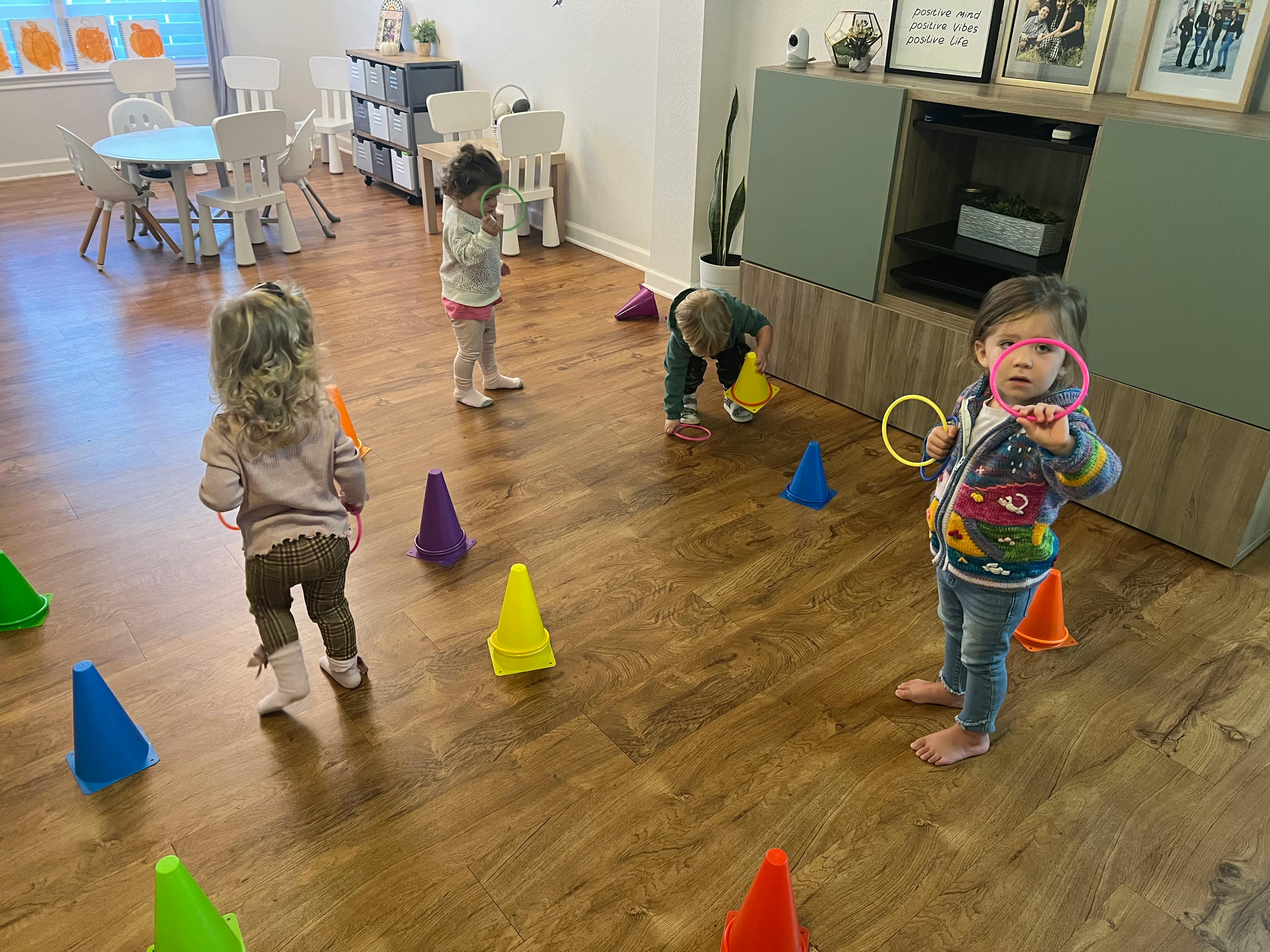 Children playing with colorful cones and rings on a wooden floor
