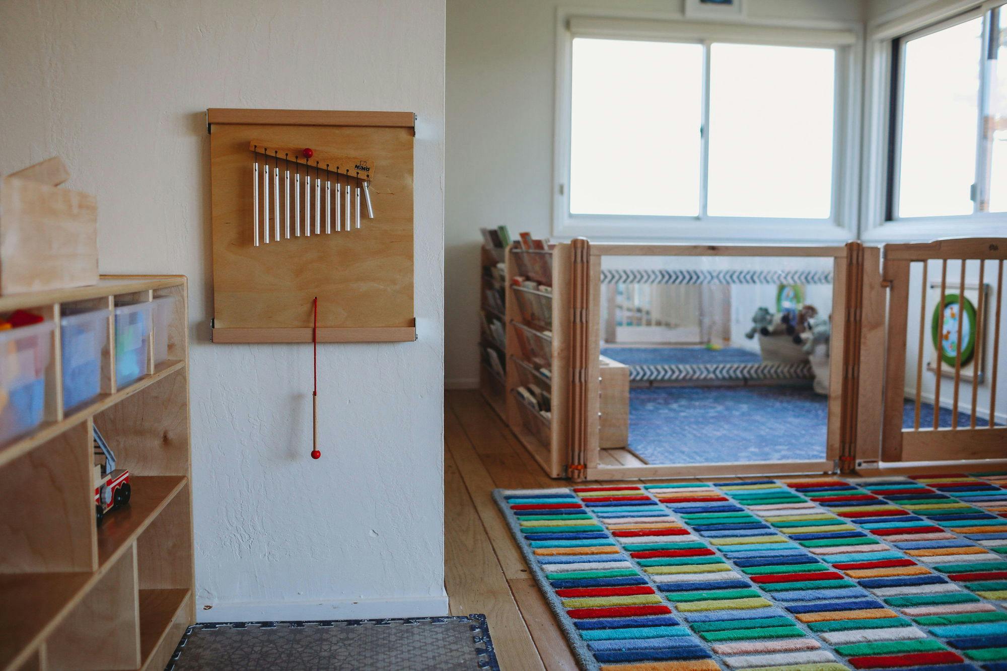 Wall-mounted xylophone next to a colorful rug and child gate