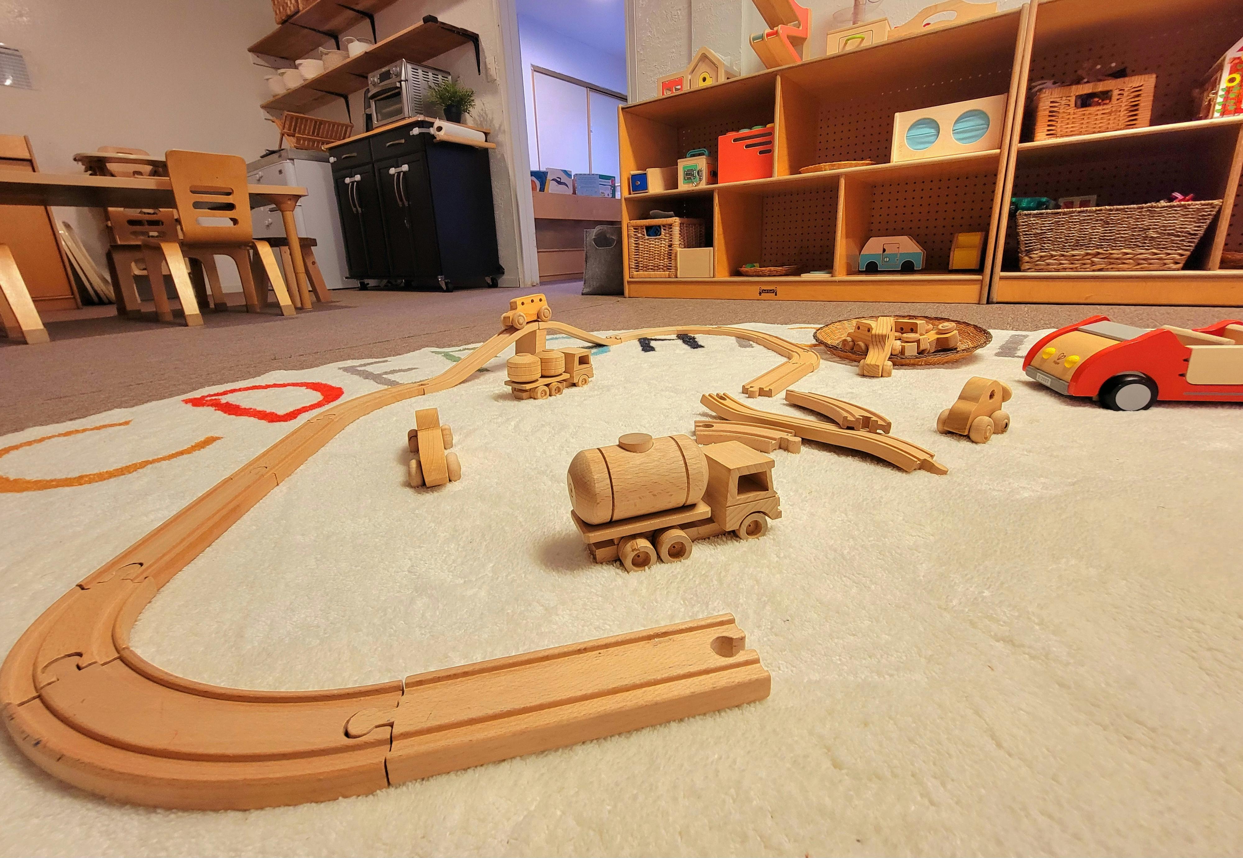 Wooden toy train set and other wooden toys on a white rug
