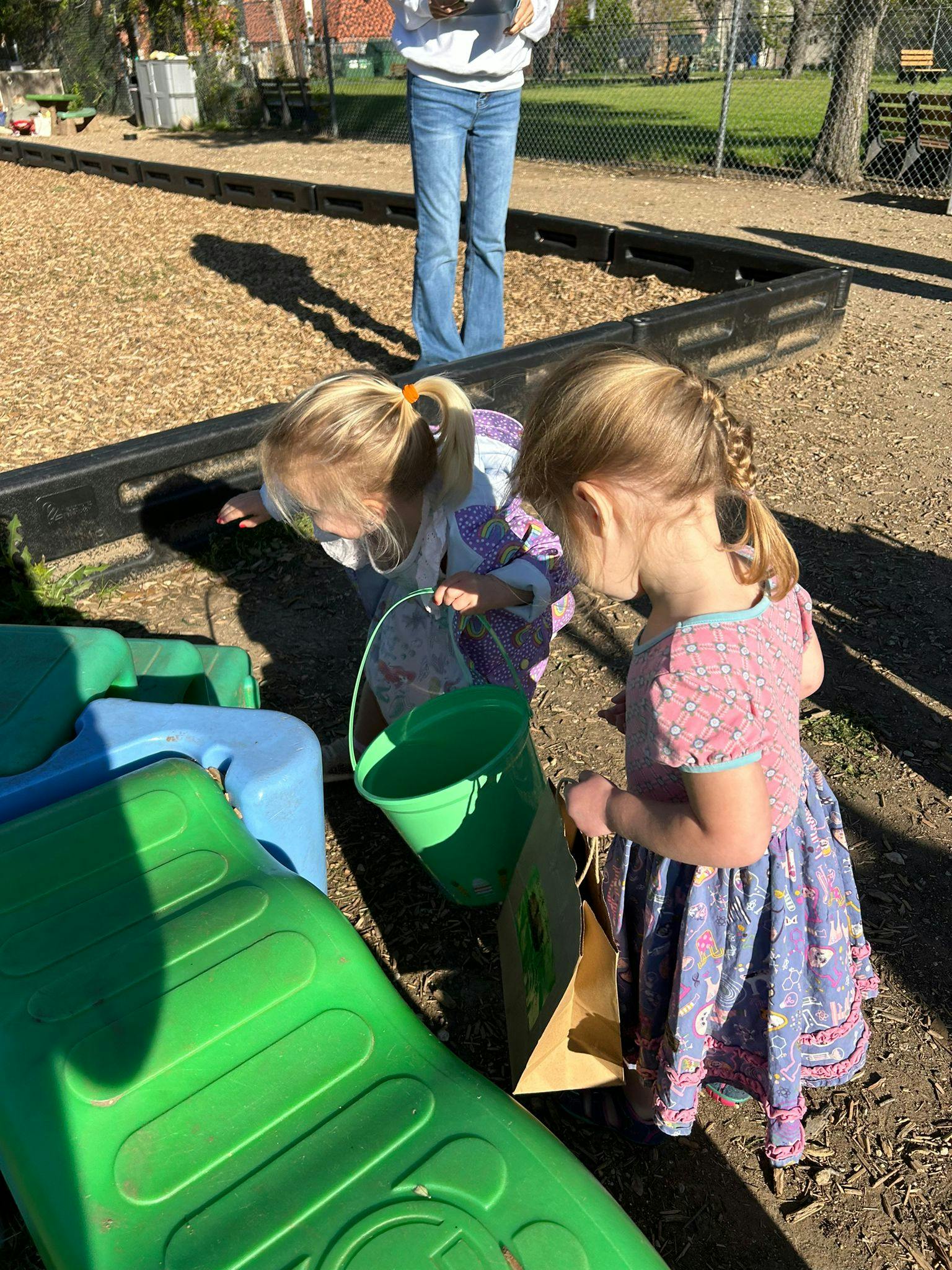 Two children playing with buckets on a playground