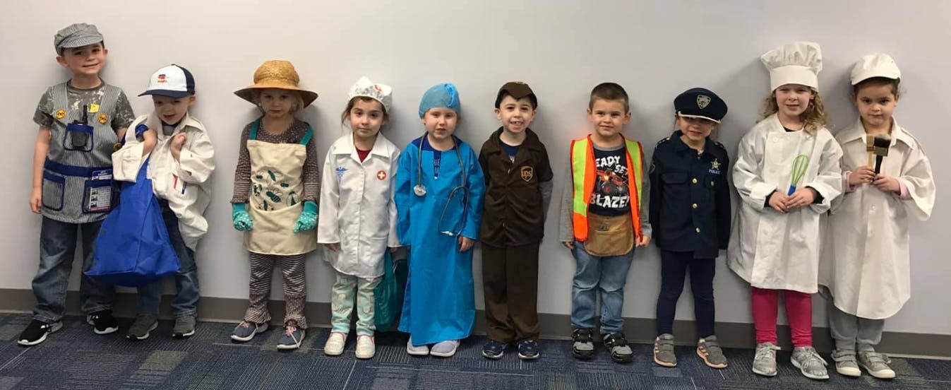 Ten children in various career costumes standing in a line