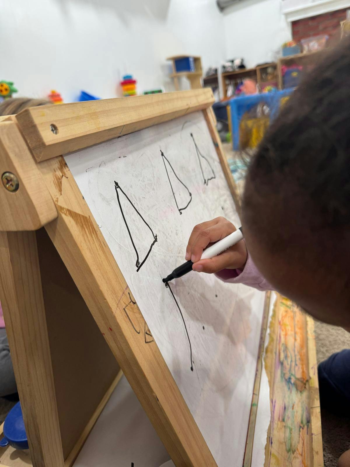 Child drawing on an easel with a marker