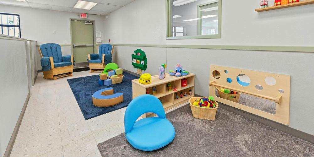Childcare room with toys and child-sized seating on area rugs
