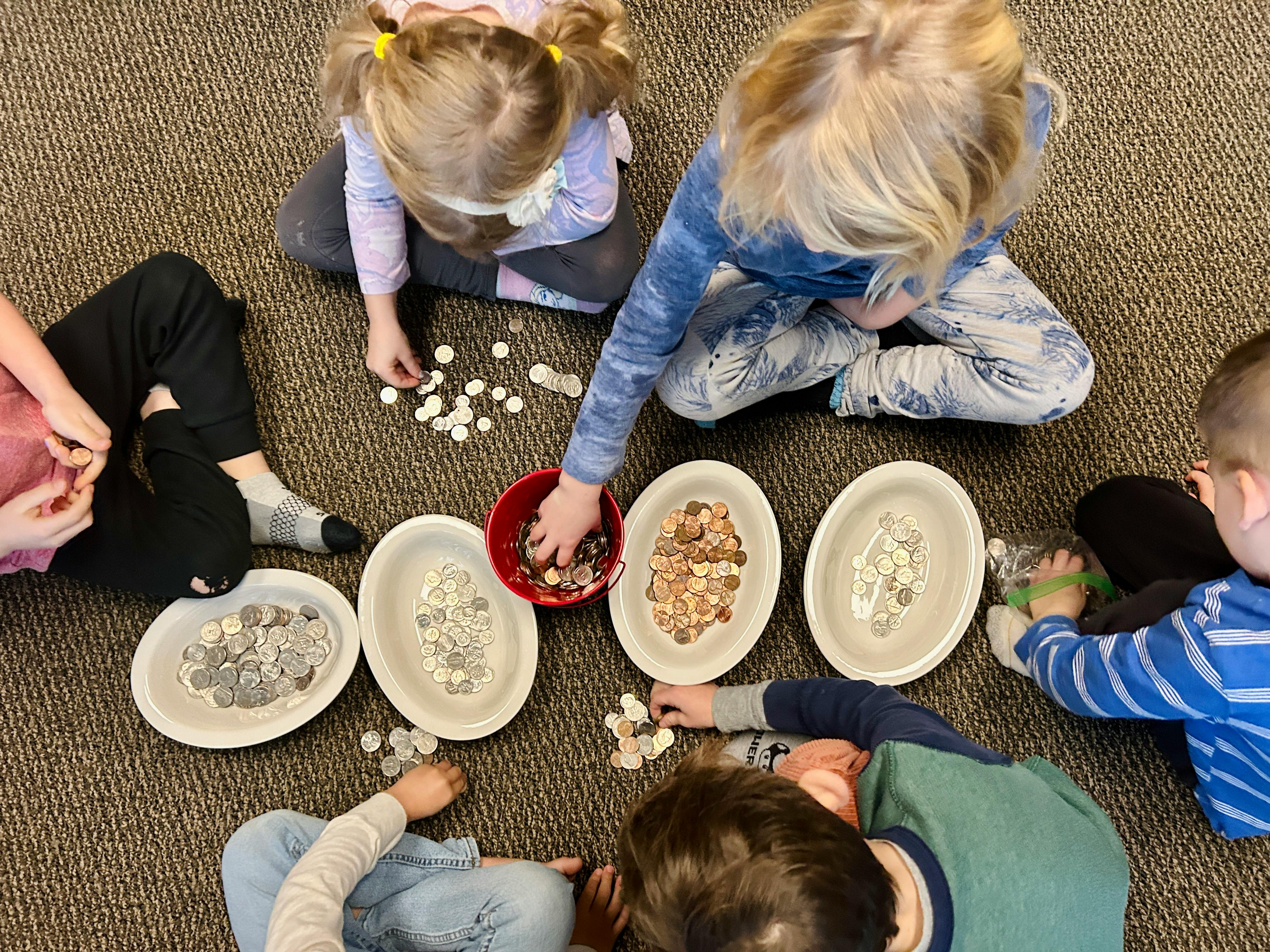 Children sorting small objects into bowls on the floor