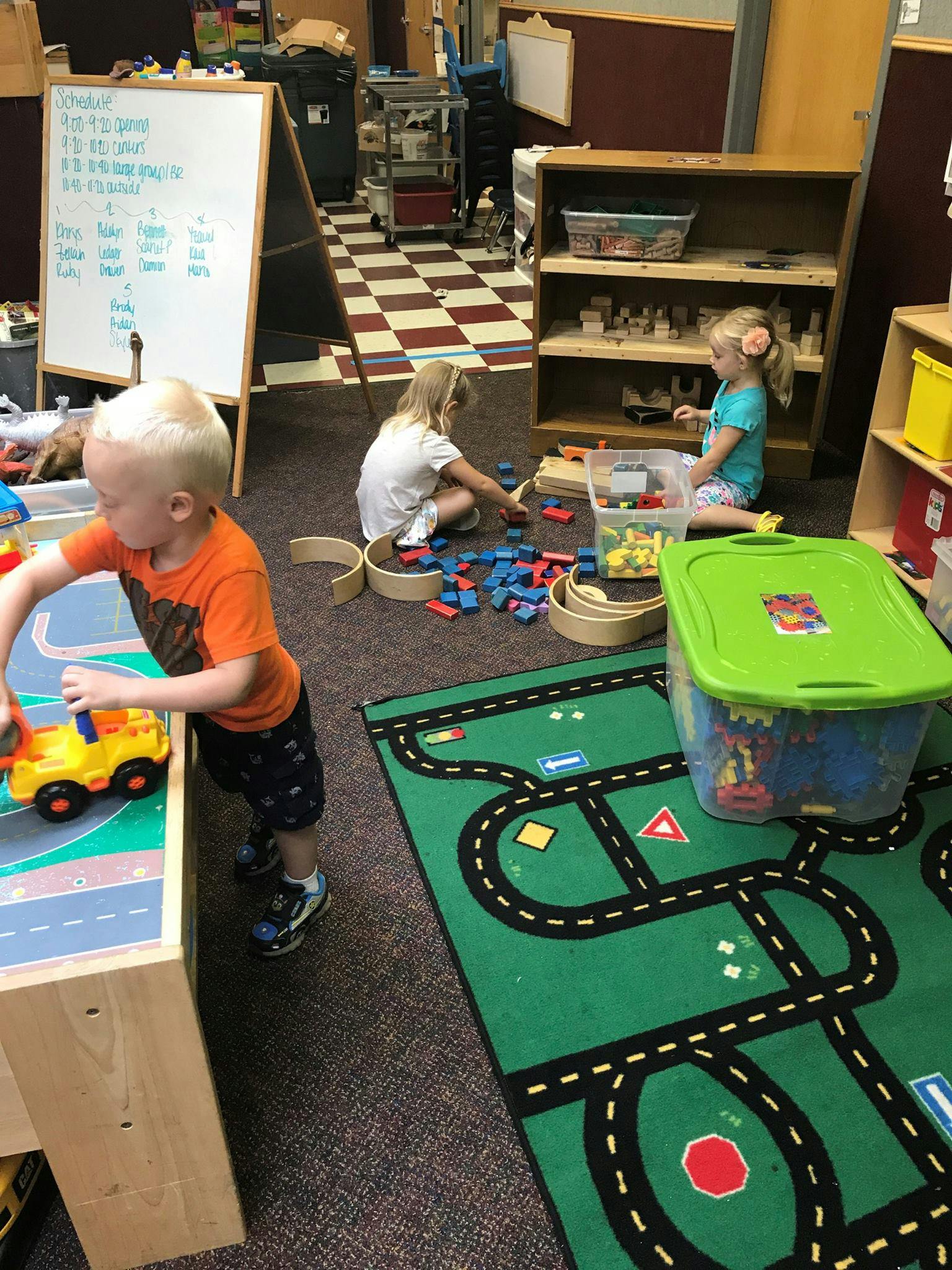 Three children playing with toys in a classroom