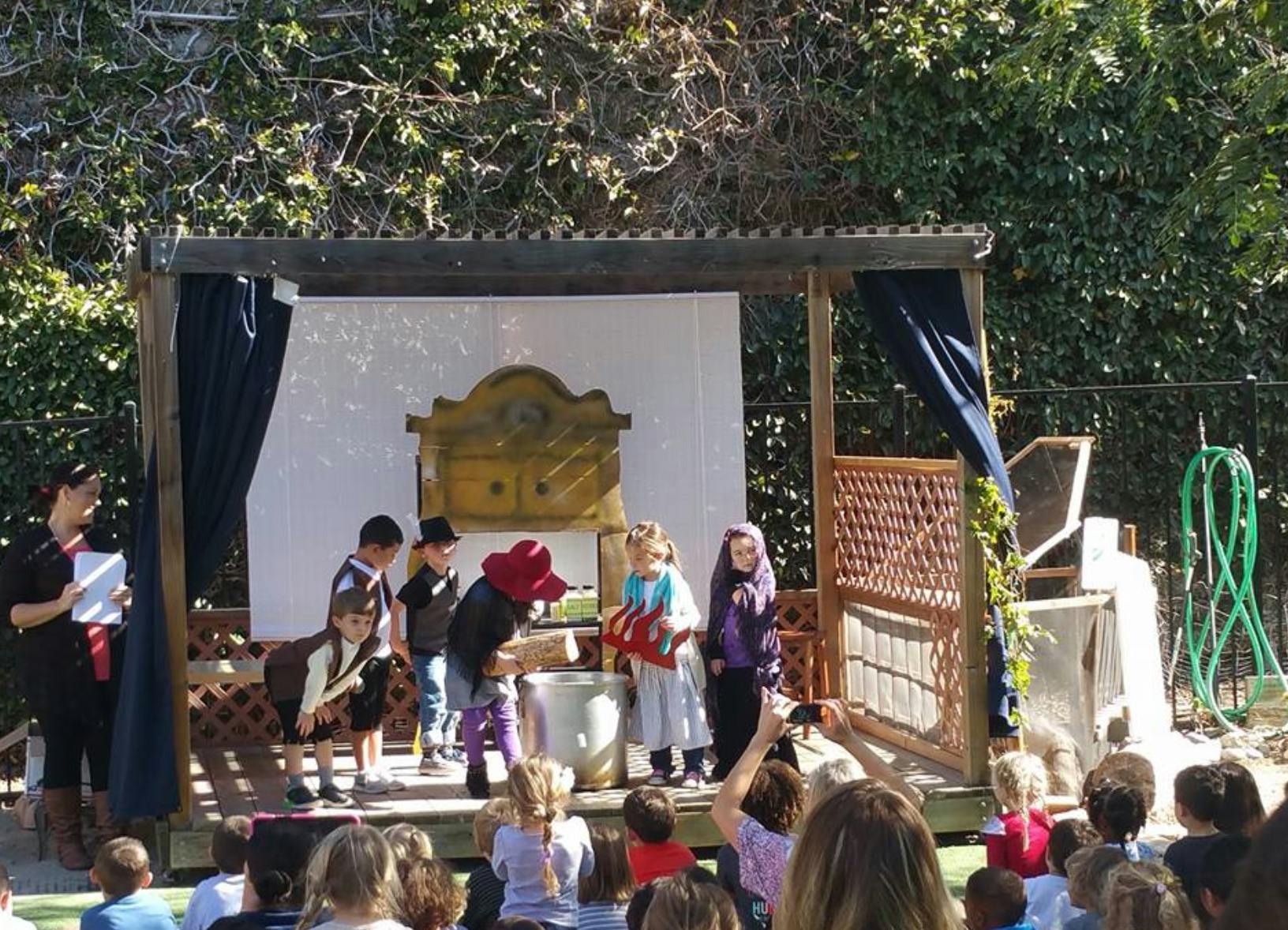 Children performing on an outdoor stage for an audience