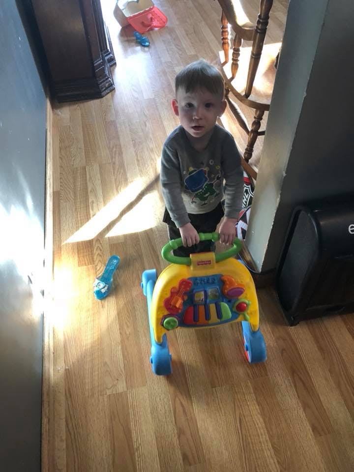 Child standing with a colorful baby walker