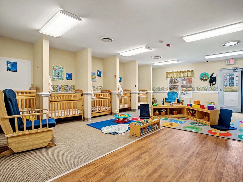 Cribs, rocking chairs, and play mats in a bright nursery room