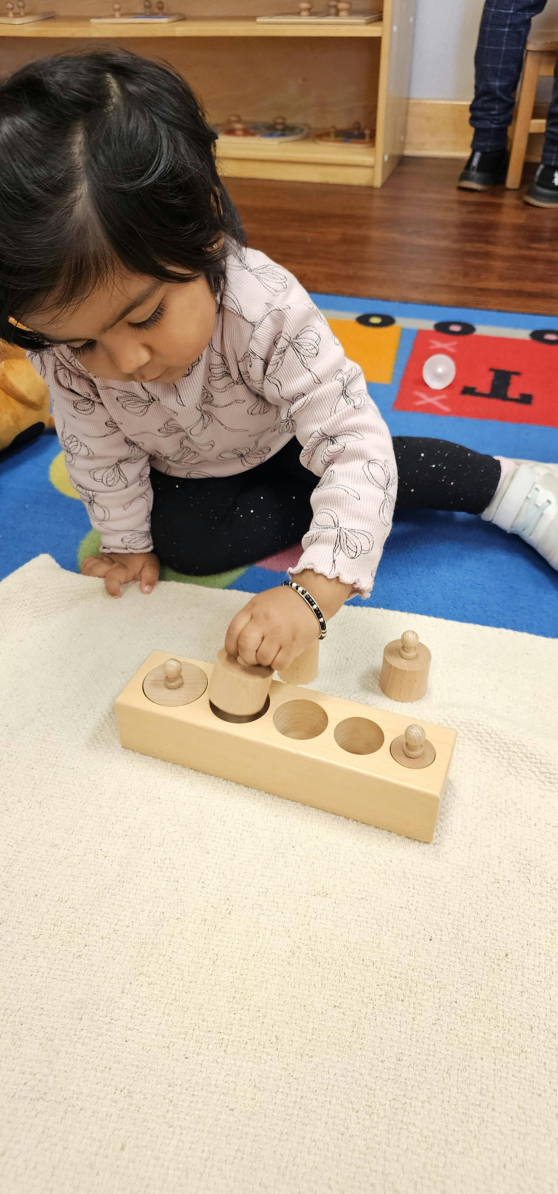 Child playing with a wooden cylinder block puzzle