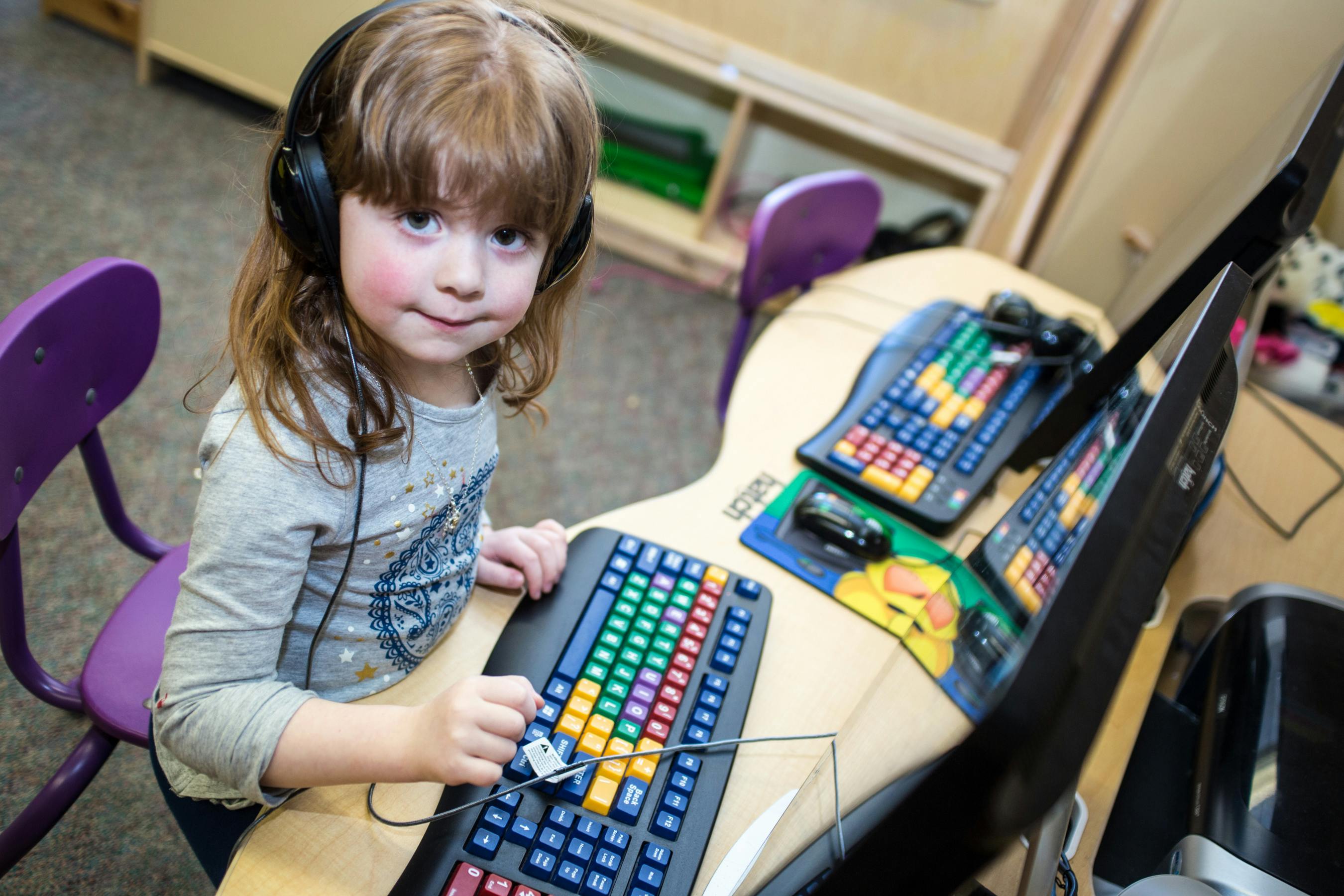 Child wearing headphones and using a colorful keyboard