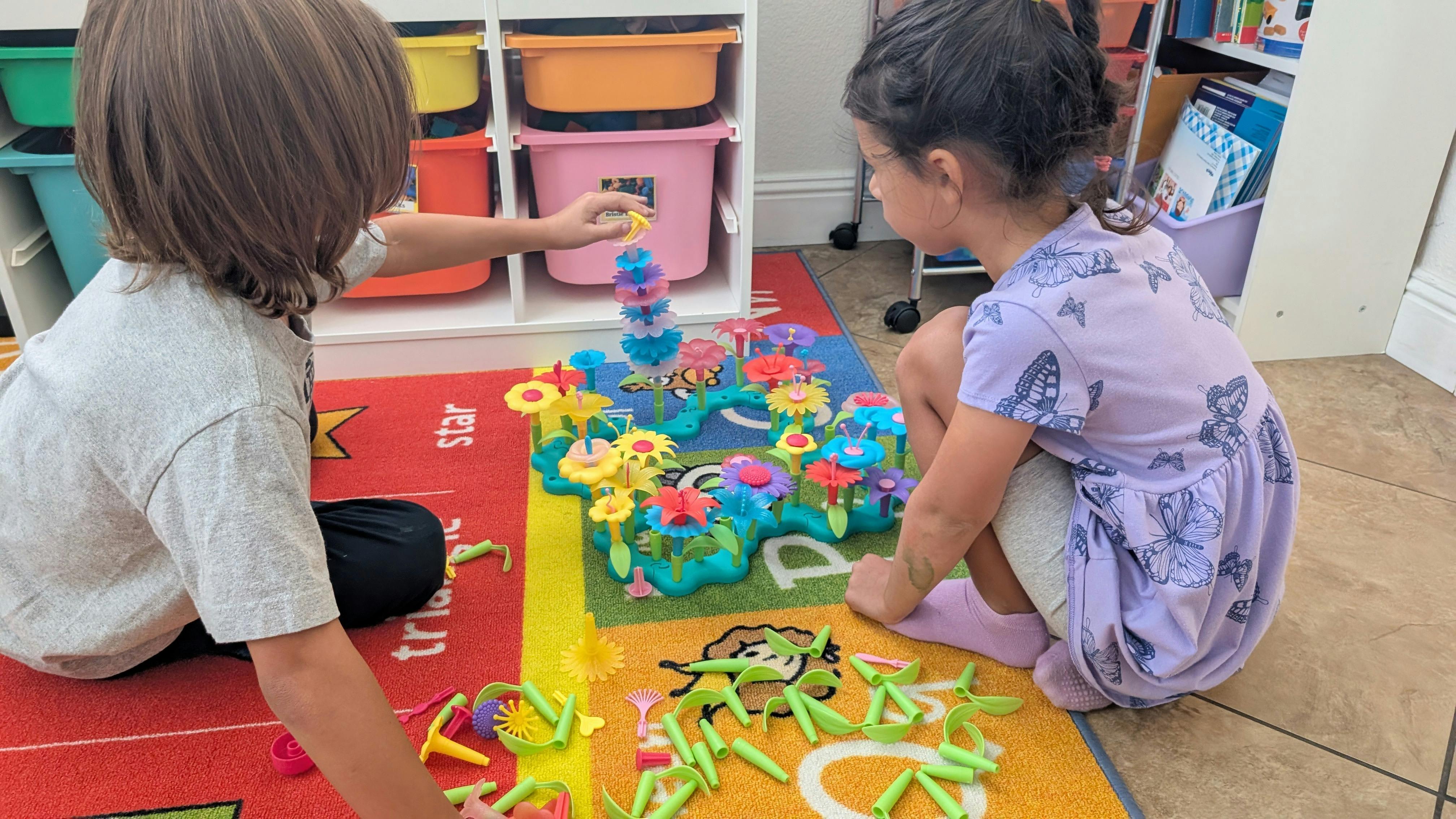Two children playing with colorful building toys on a rug