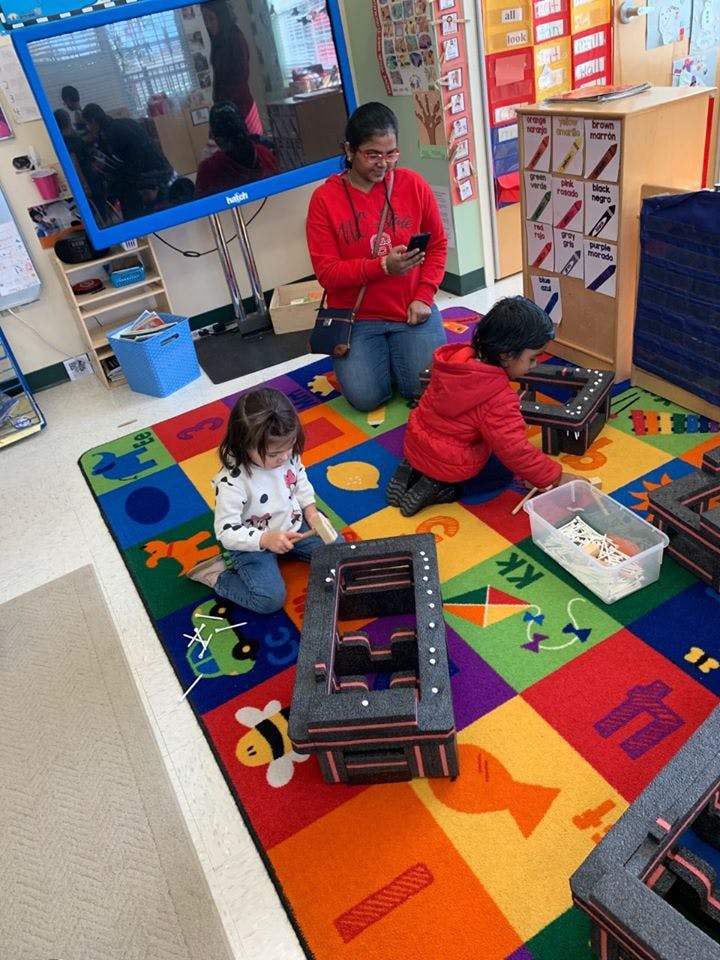 Adult and two children on a colorful rug playing with building blocks