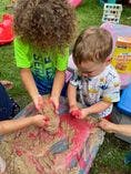 Two children playing with sand and water in a bin