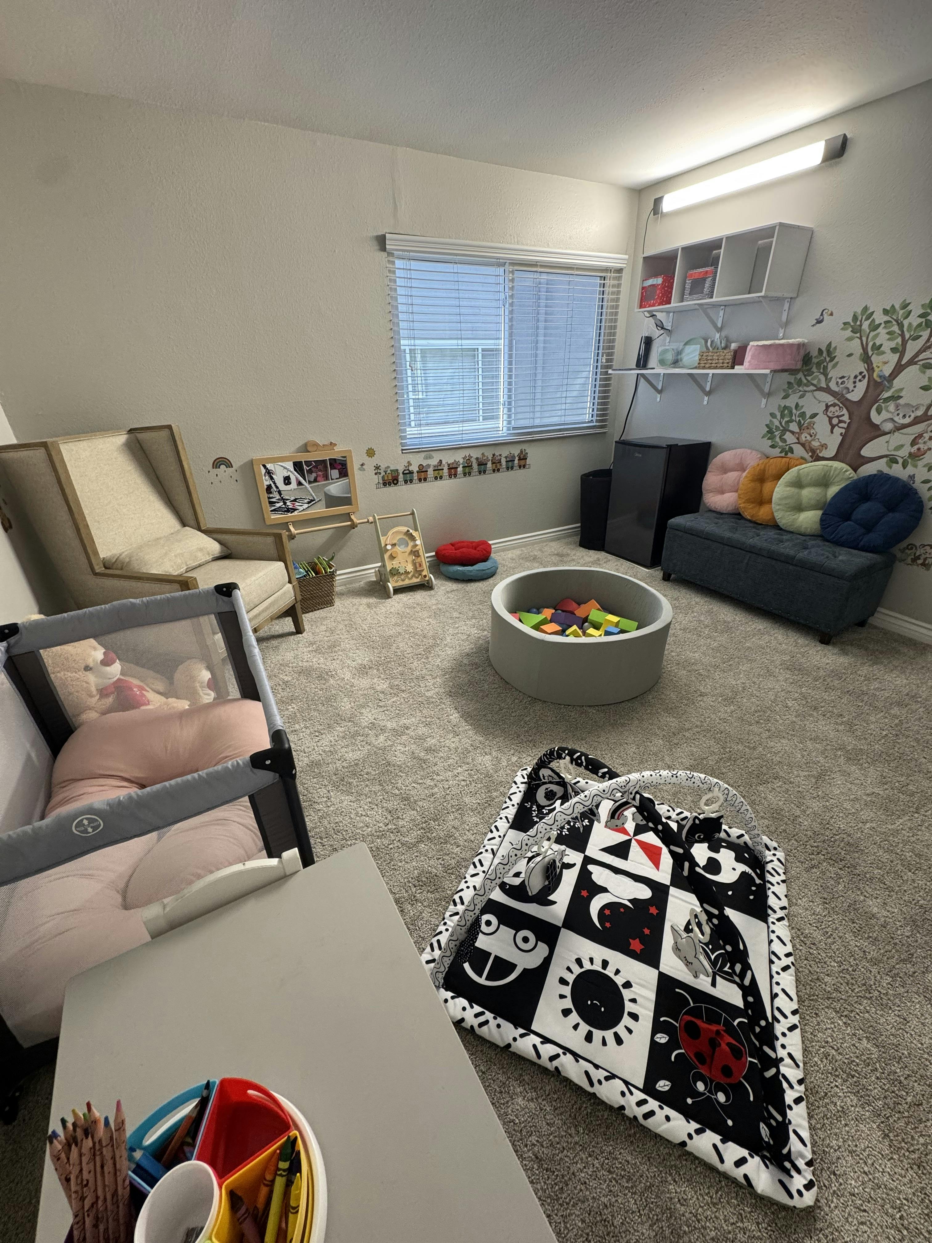 Child playroom with a floor play mat, foam ball pit, and toy furniture