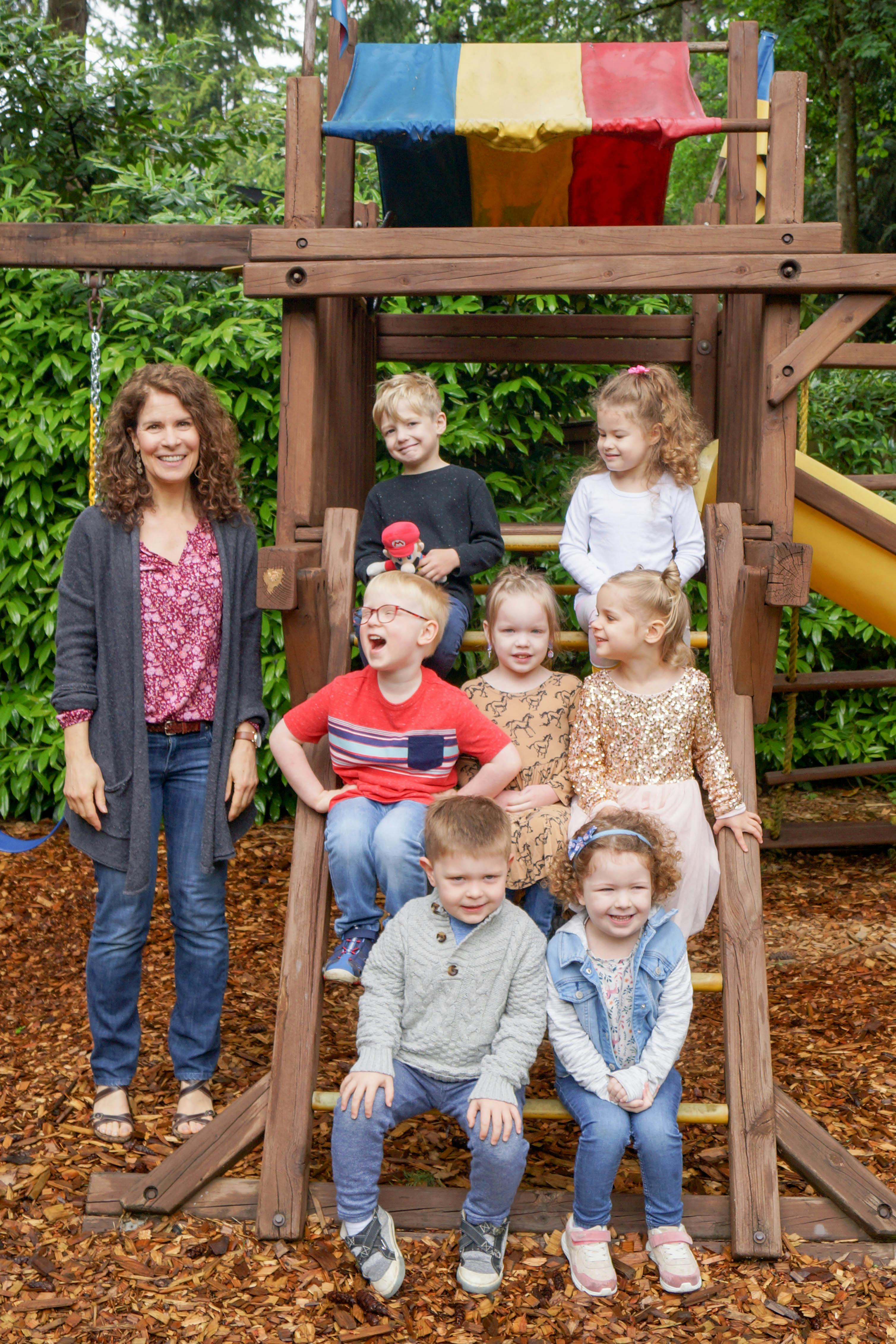 Person and multiple children on and around a wooden playground structure