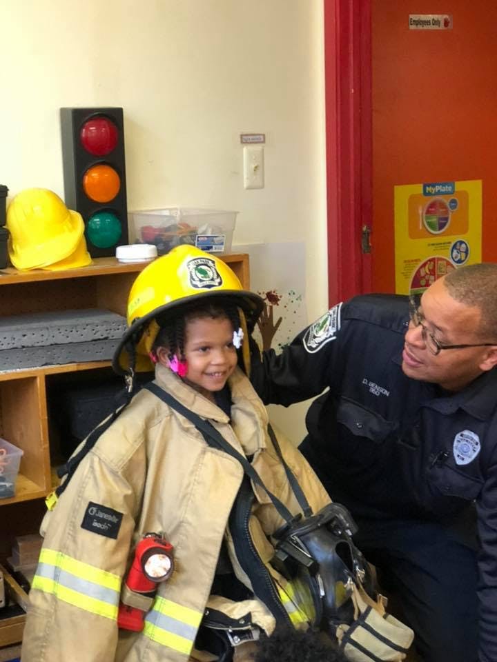 Child in firefighter gear with an adult in uniform