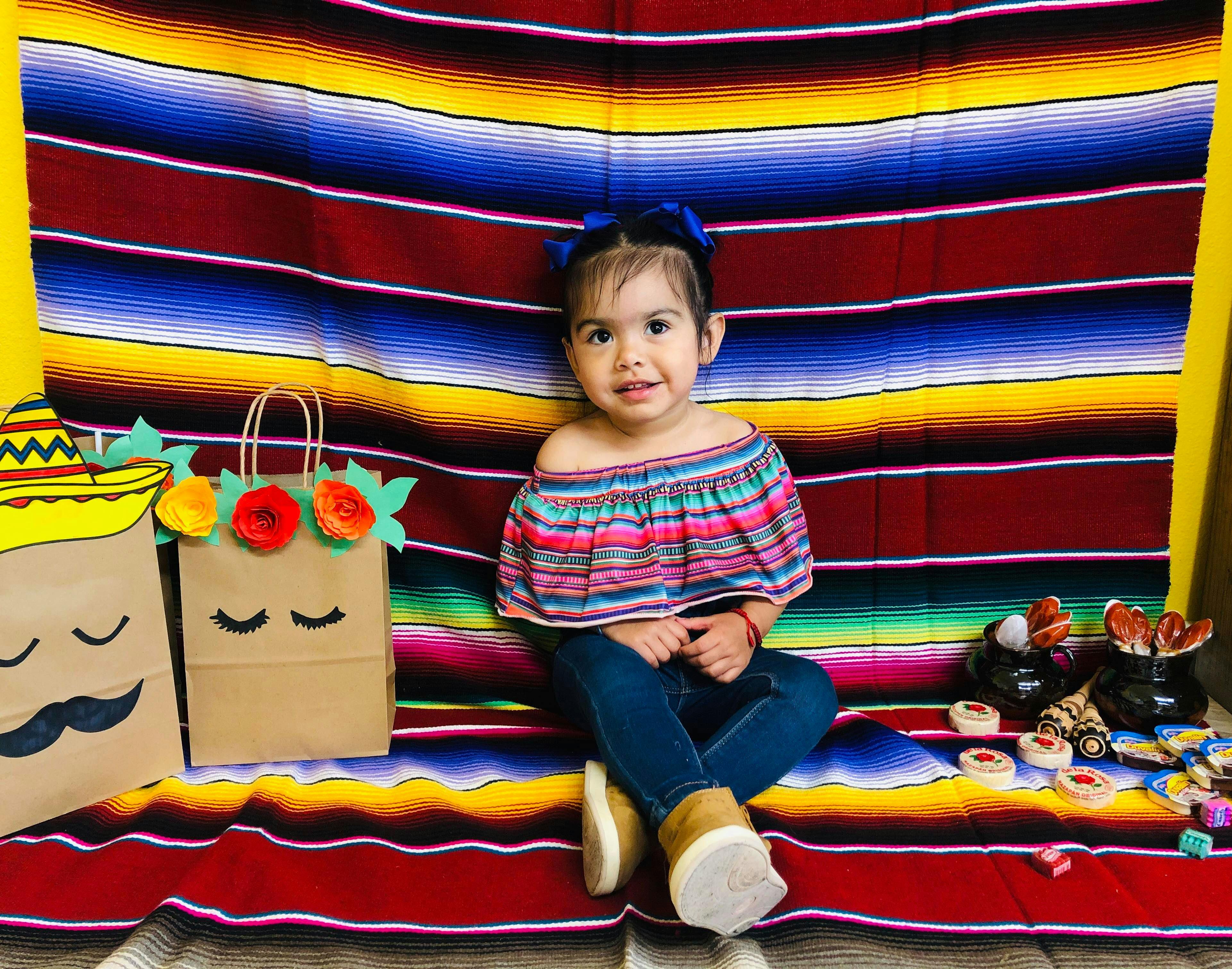 Child sitting in front of a striped blanket with decorative bags
