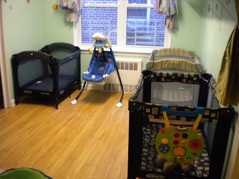 Three baby cribs and a baby swing in a room
