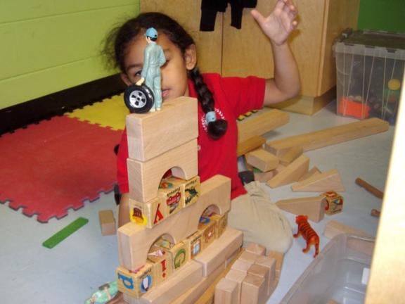 Child playing with wooden blocks and small figures