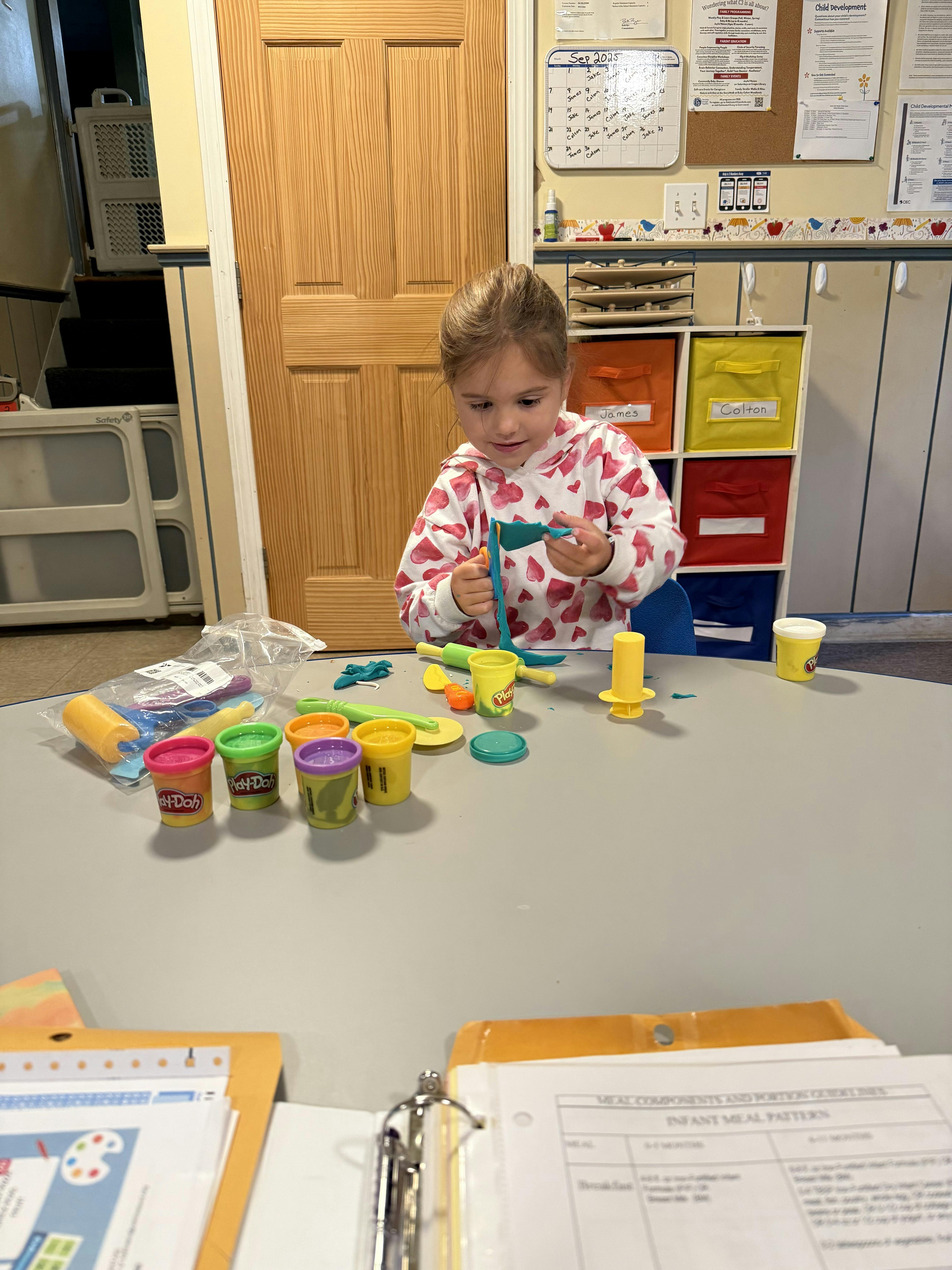 Child playing with modeling clay and tools at a table