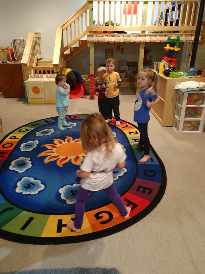 Children standing on a colorful alphabet rug in a play area
