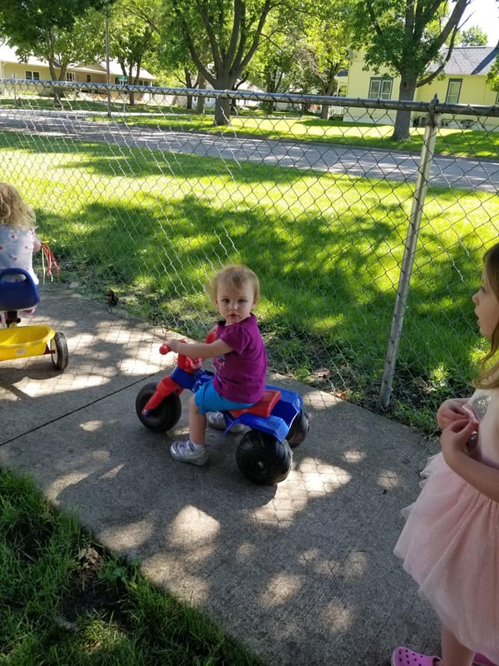 Child on a toy tricycle on a sidewalk