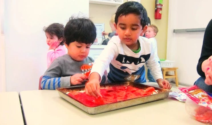Two children playing with red items in a tray