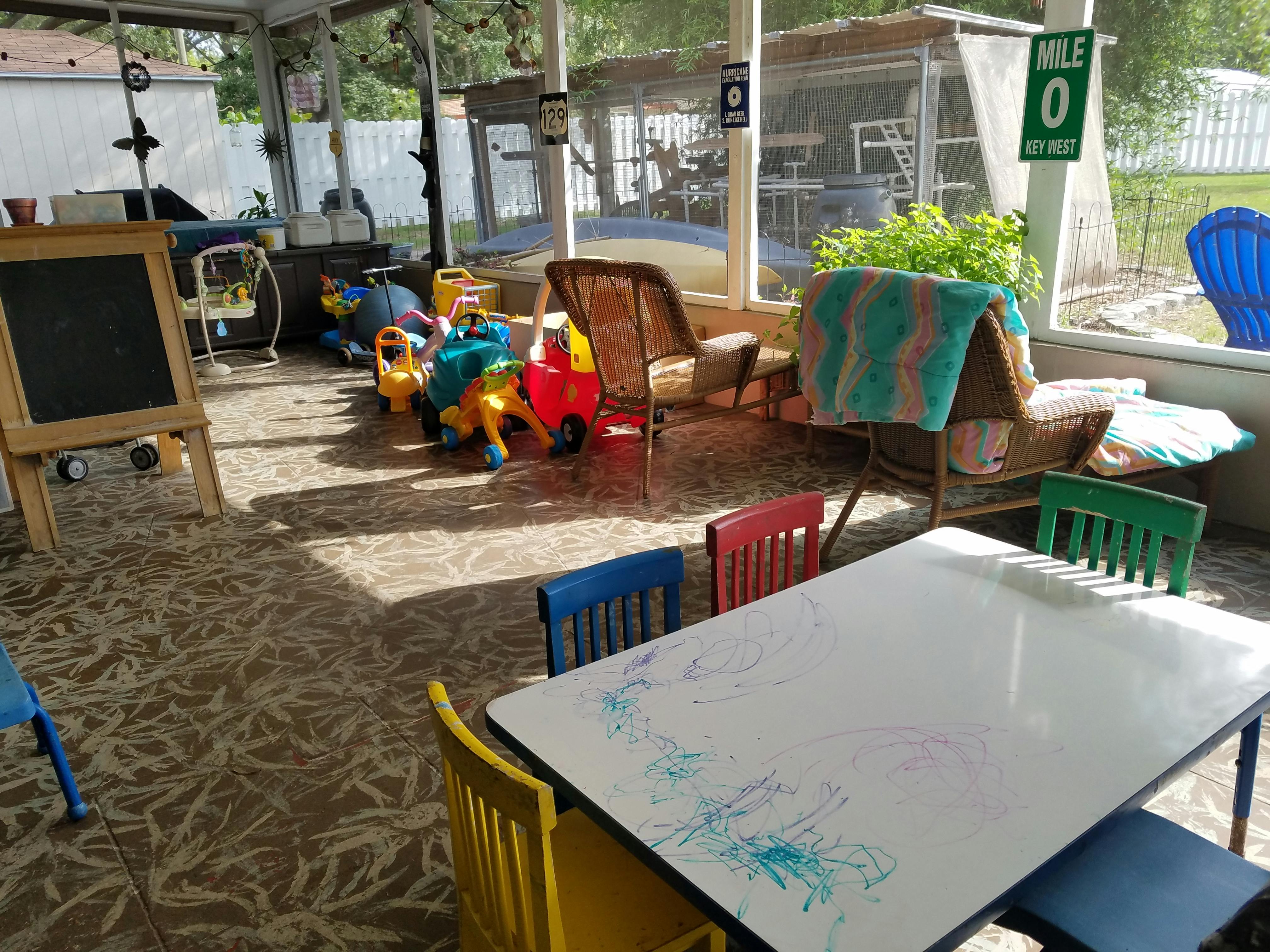 Playroom with small table and chairs, chalkboard, and ride-on toys