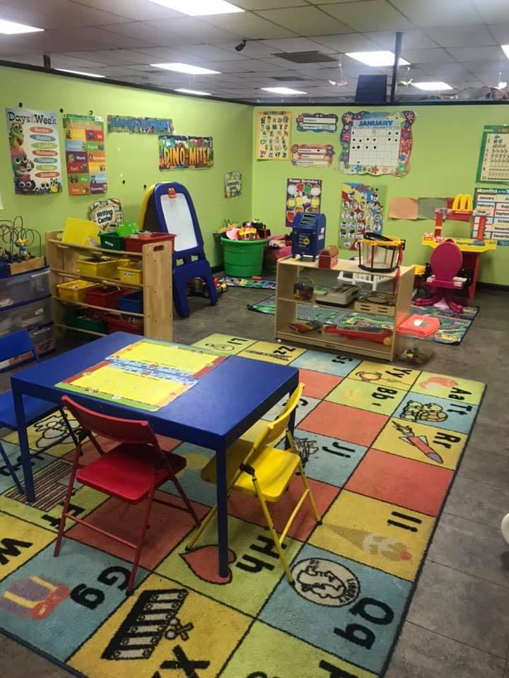 A colorful classroom with small tables and chairs, toys, and educational posters