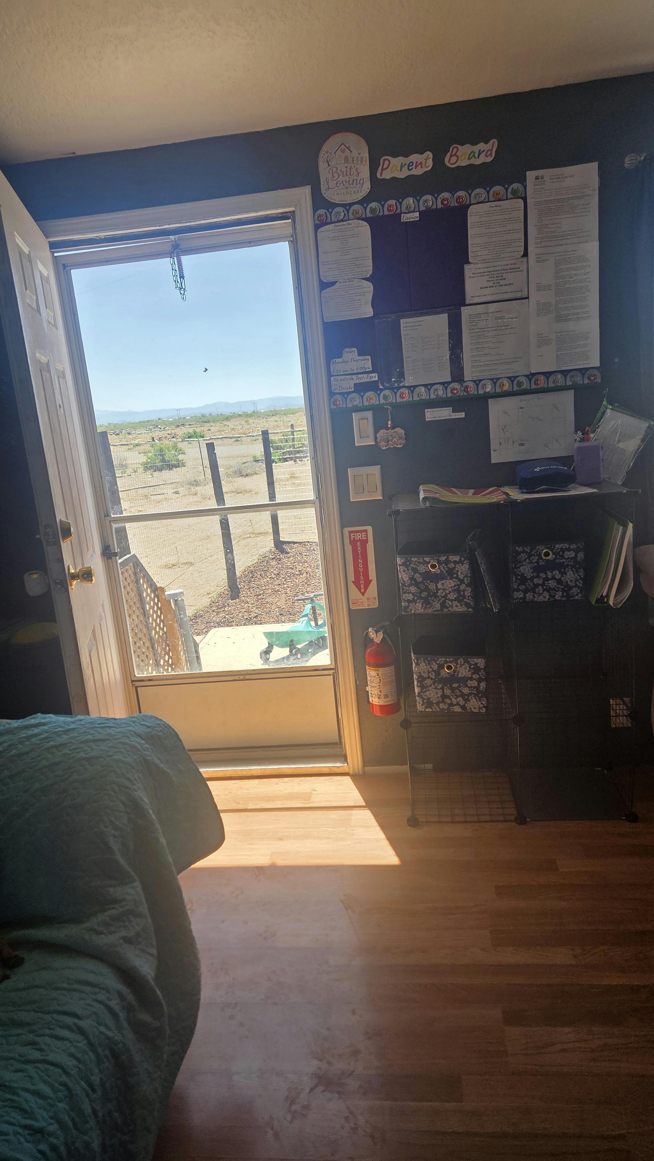 Childcare room with a parent board and open door to an outdoor area