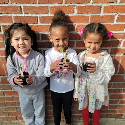 Three children holding small potted plants