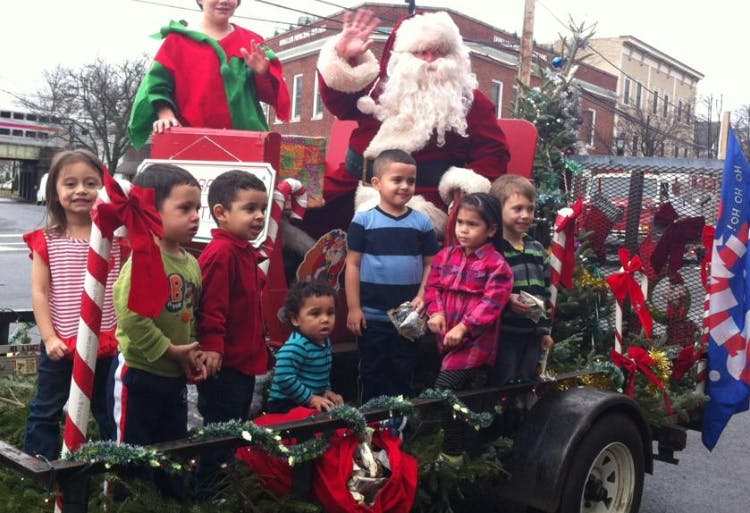 Santa Claus waving from a float with several children